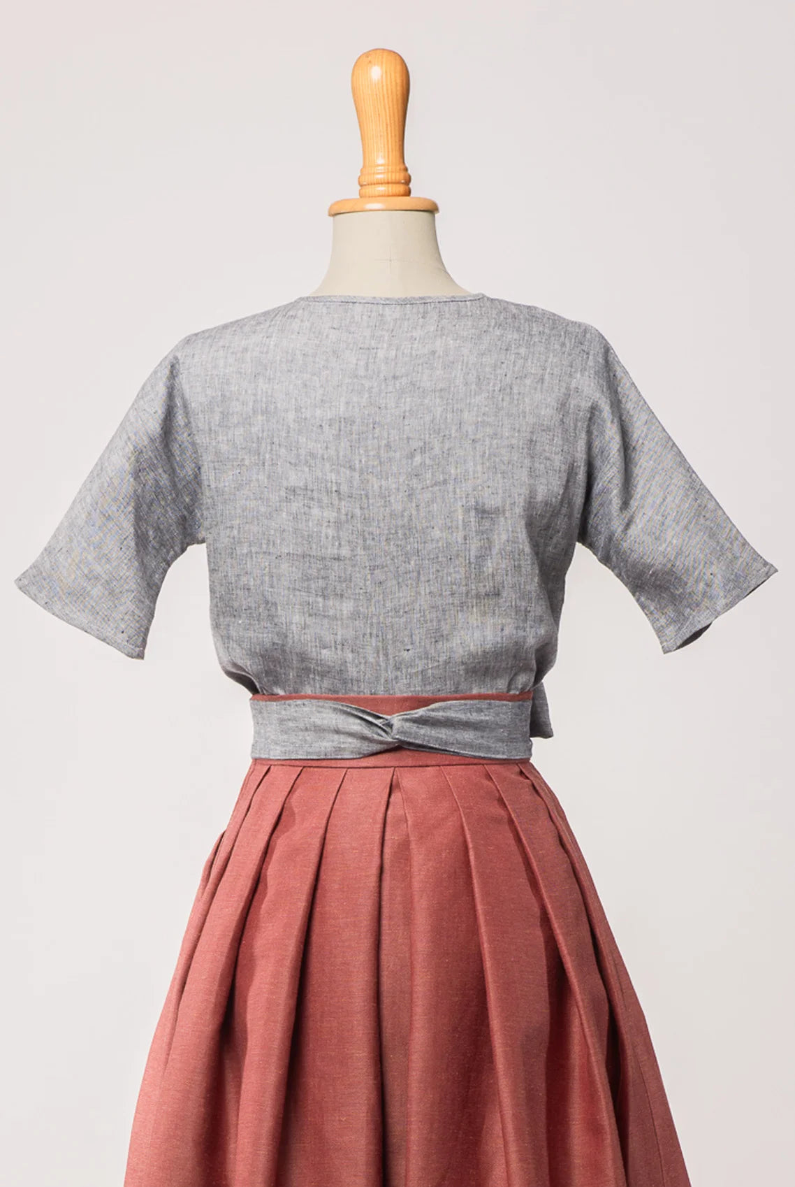 Bluse Romy aus blaugrauem Bio-Leinen, kombiniert mit Trachtenrock Charlie und farblich passendem Schürzenband – Rückansicht auf Büste, nachhaltig gefertigt von Zirbenfux