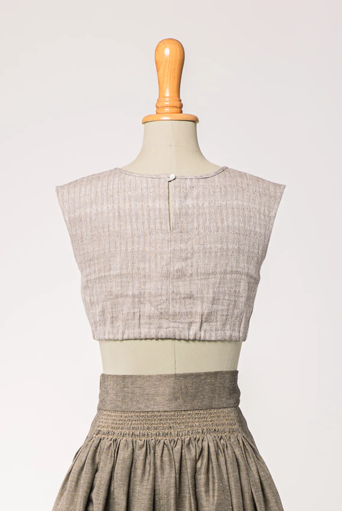 Nahaufnahme von Dirndlbluse Charlie aus naturfarbenem Bio-Leinen mit eingewebtem Muster, kombiniert mit Rock Marlene in goldbraun – Rückansicht auf Büste, nachhaltig gefertigt von Zirbenfux