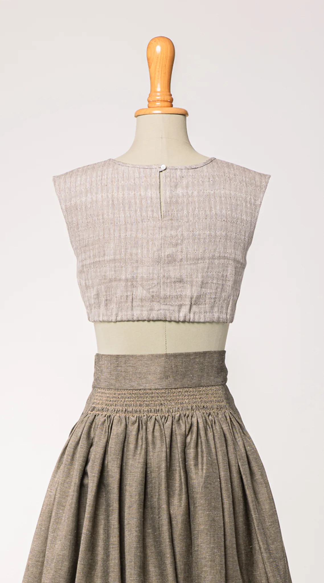 Nahaufnahme von Dirndlbluse Charlie aus naturfarbenem Bio-Leinen mit eingewebtem Muster, kombiniert mit Rock Marlene in goldbraun – Rückansicht auf Büste, nachhaltig gefertigt von Zirbenfux