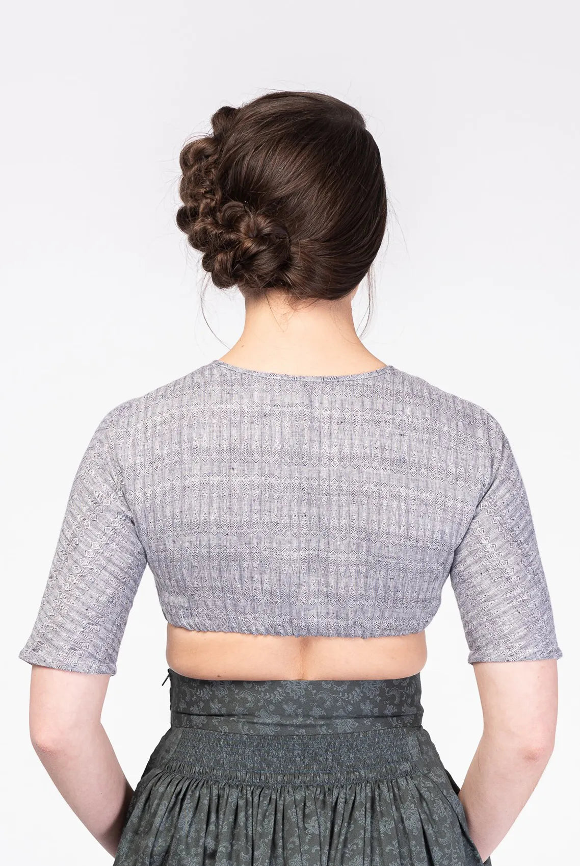 Dirndlbluse Romy aus blaugrauem Bio-Leinen mit eingewebtem Muster – Rückansicht am Model, nachhaltig gefertigt von Zirbenfux