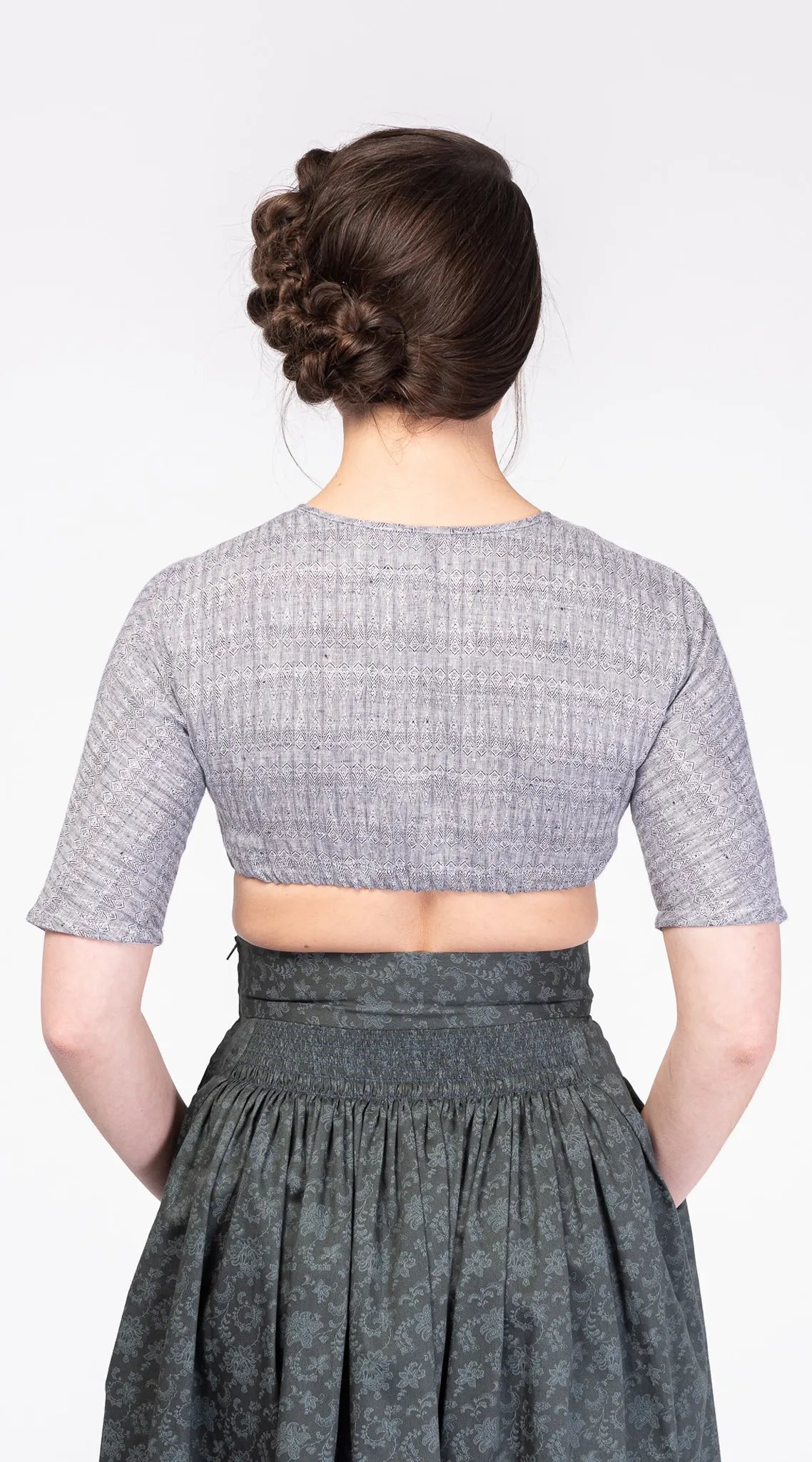 Dirndlbluse Romy aus blaugrauem Bio-Leinen mit eingewebtem Muster – Rückansicht am Model, nachhaltig gefertigt von Zirbenfux