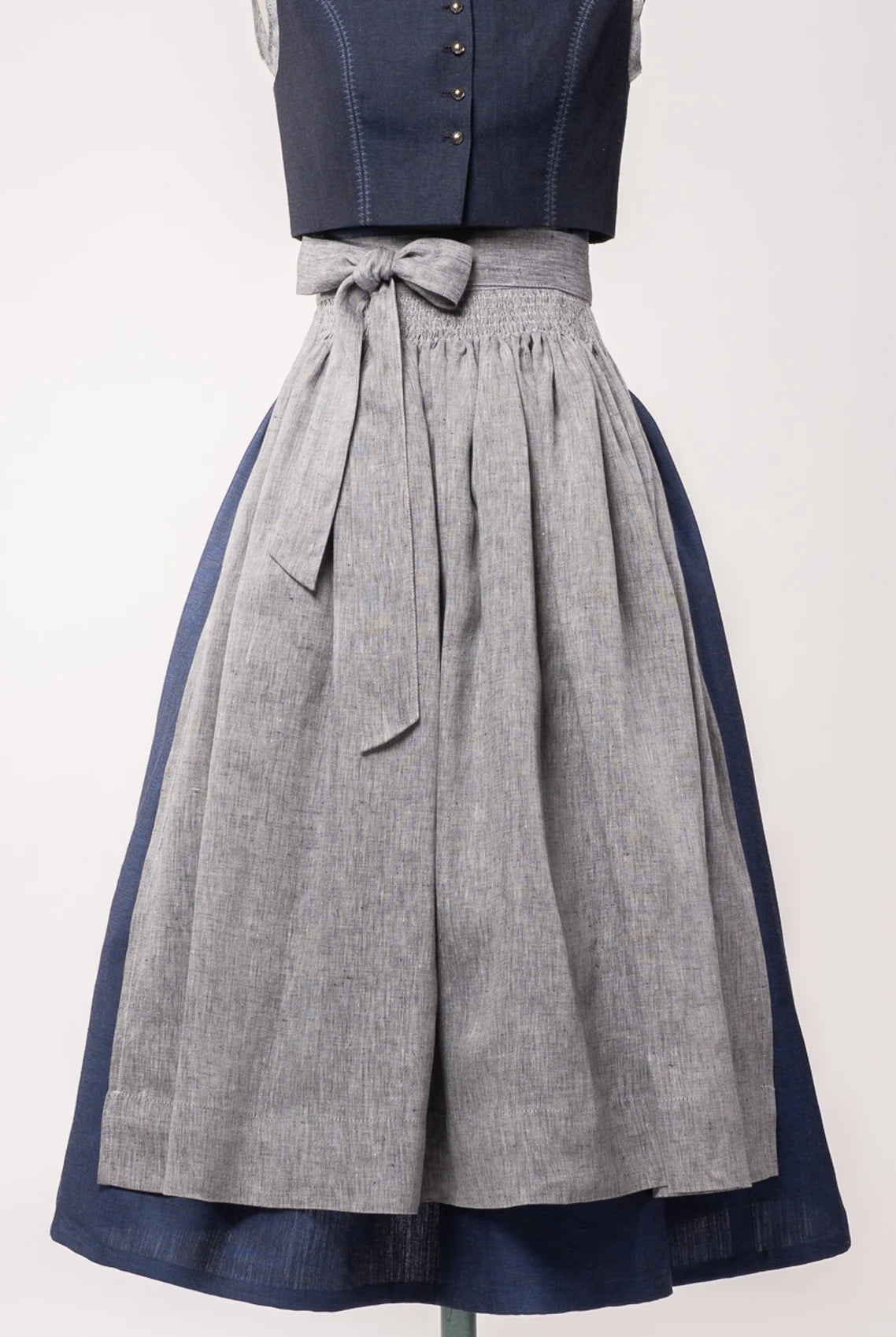 Dirndlschürze aus blaugrauem Bio-Leinen auf Büste – Frontansicht, handgefertigt & nachhaltig von Zirbenfux