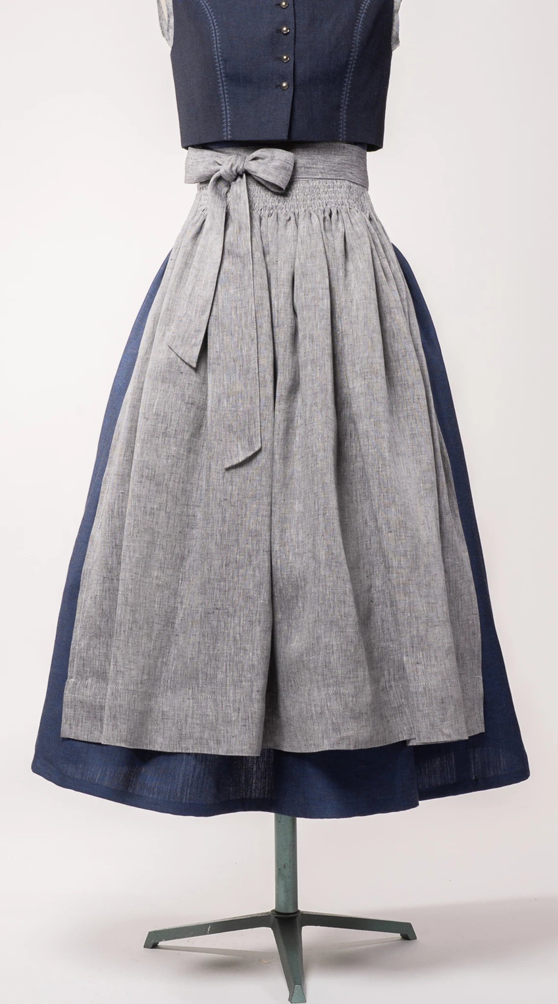 Dirndlschürze aus blaugrauem Bio-Leinen auf Büste – Frontansicht, handgefertigt & nachhaltig von Zirbenfux
