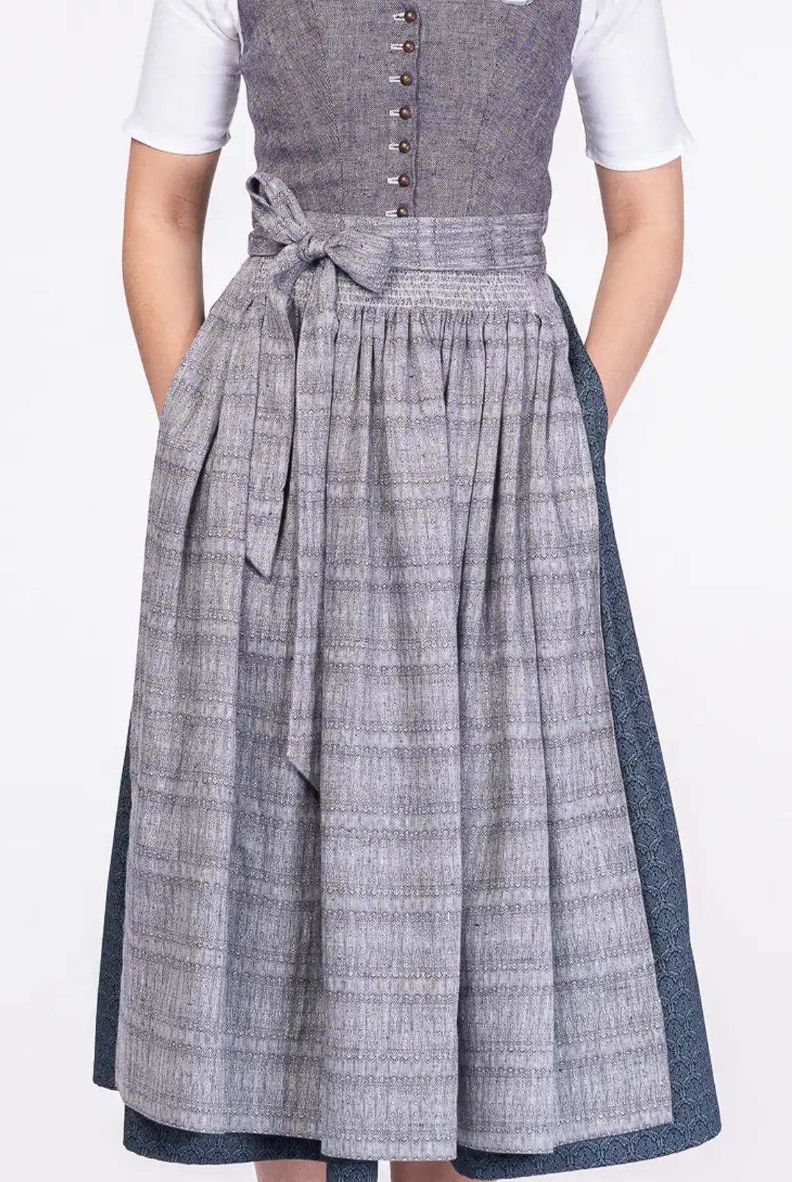 Dirndlschürze aus blaugrauem Bio-Leinen mit eingewebtem Muster – Nahaufnahme Frontansicht am Model, nachhaltig gefertigt von Zirbenfux