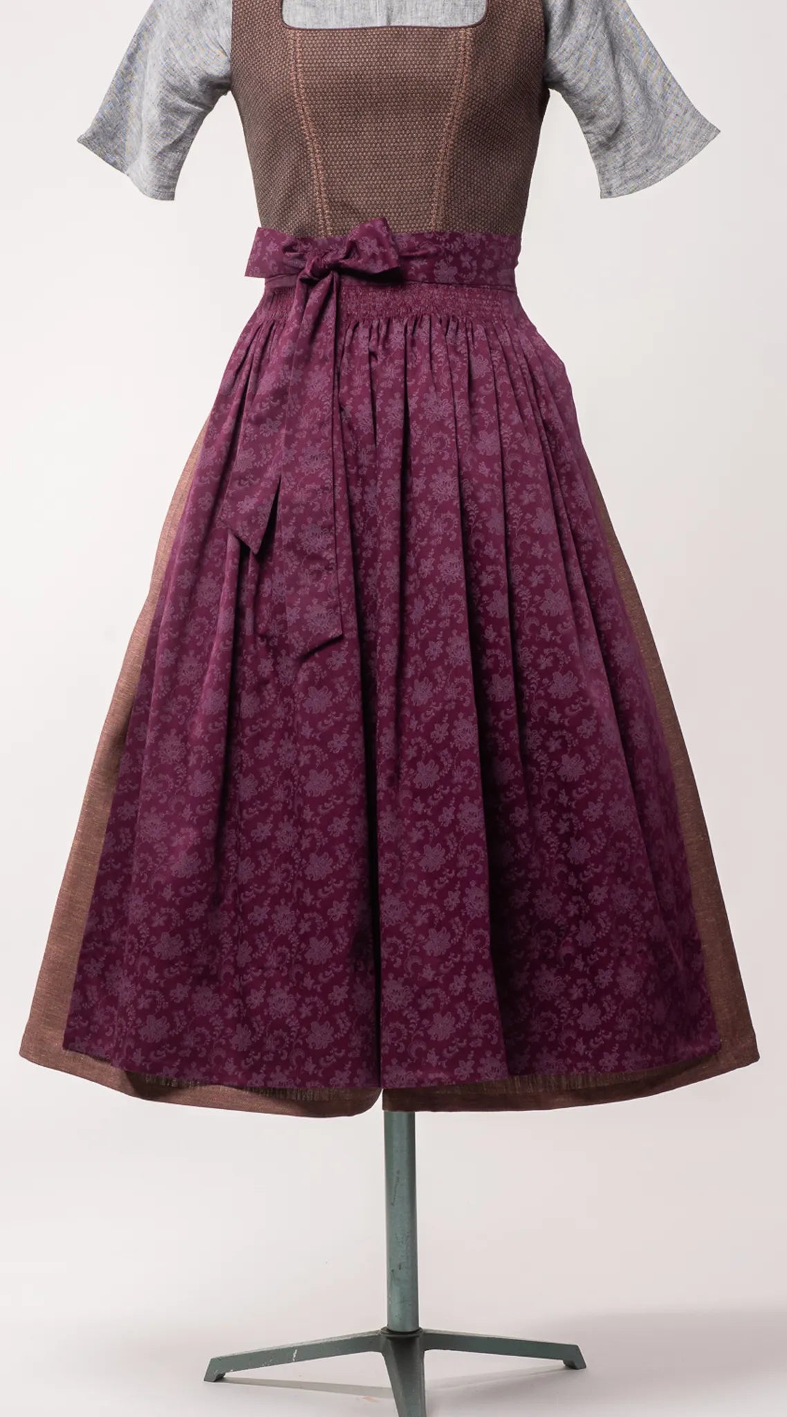 Dirndlschürze aus brombeerfarbener Baumwolle mit Blumenrankenmuster – Nahaufnahme der Frontansicht auf Büste, handgefertigt in München von Zirbenfux
