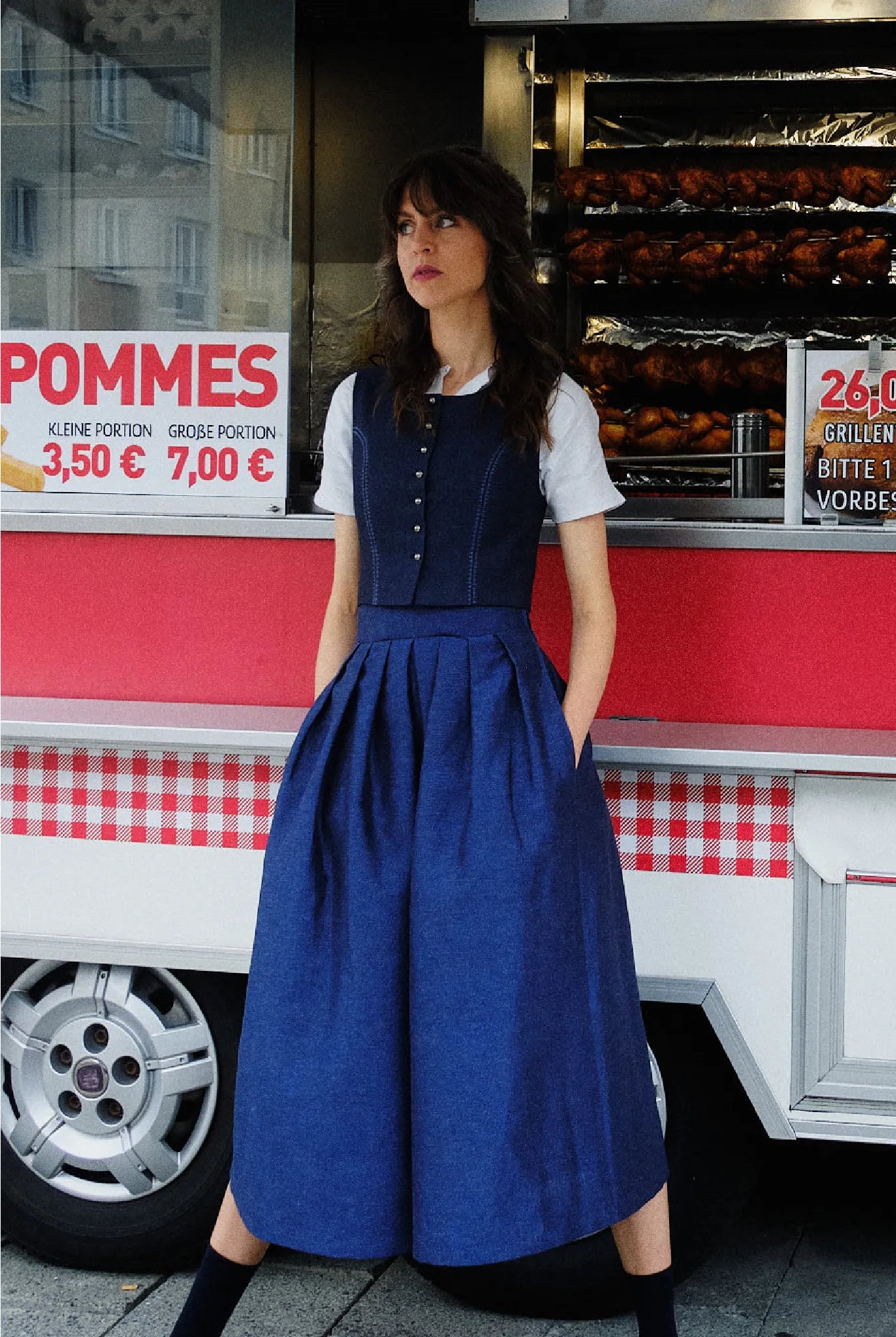 Hosenrock Audrey mit Fuxerl Charlie im Set in Dunkelblau aus Leinen, Model lässig mit dem Rücken an einen Straßenimbiss gelehnt und die Hände in den Taschen, urban inszeniert von Zirbenfux.
