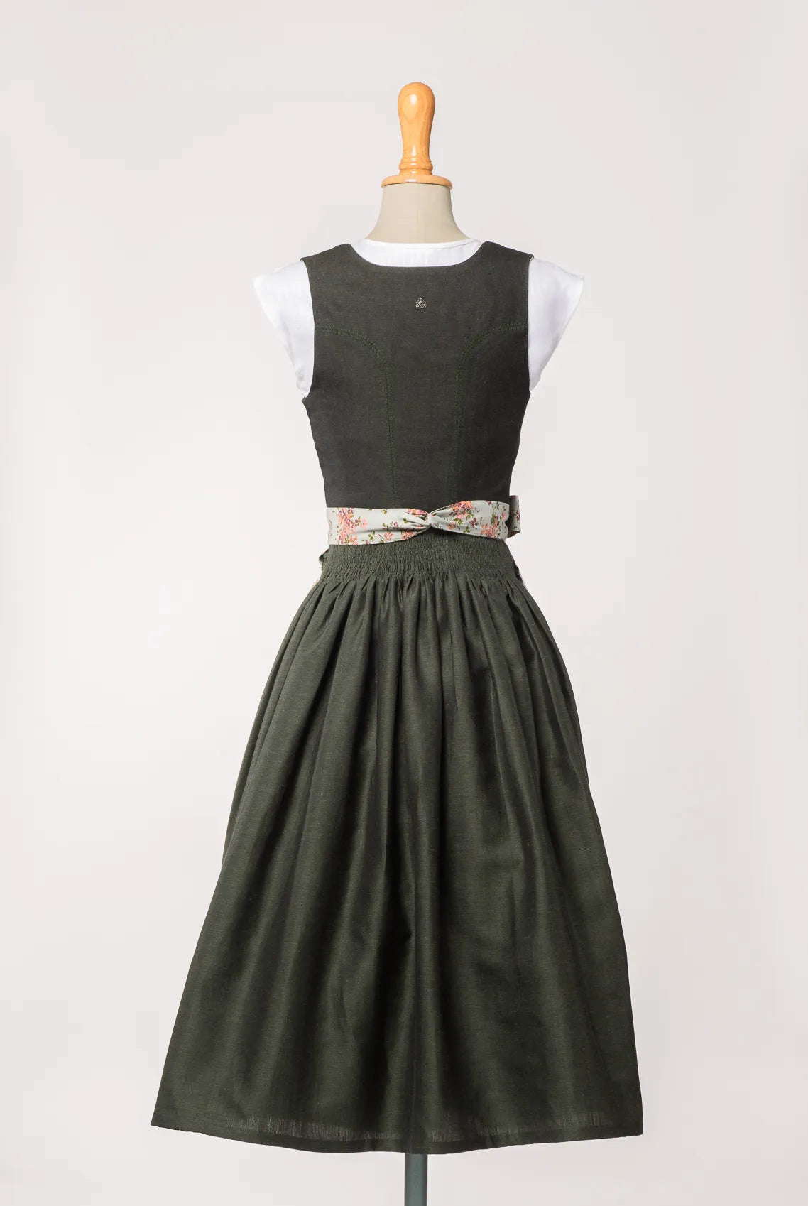 Mieder Ava aus dunkelgrüner Leinen-Schurwolle-Mischung, kombiniert mit Schürze mit Blumenmuster – Rückansicht auf Büste, handgefertigt in München von Zirbenfux