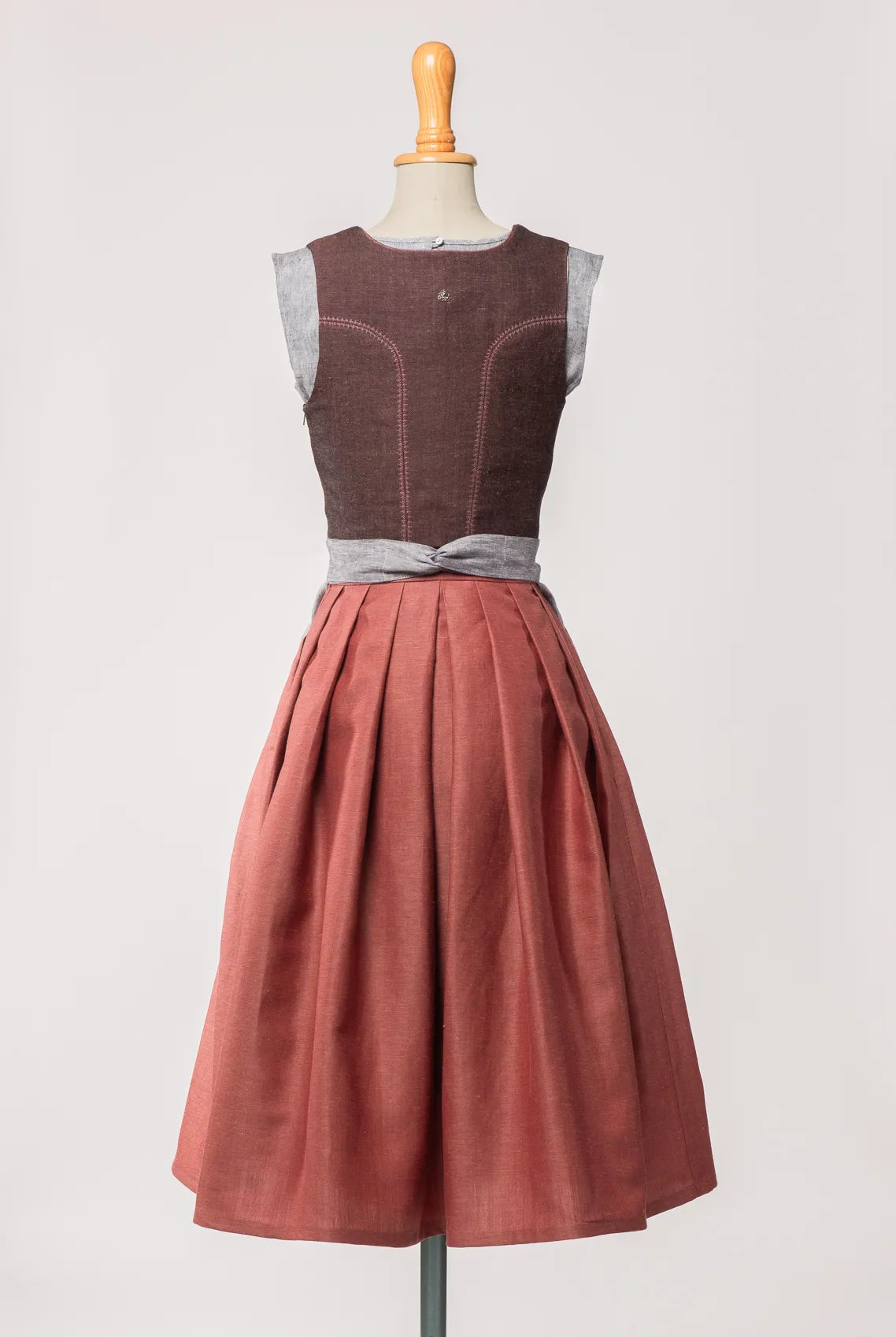 Mieder Ava aus Leinen-Schurwolle-Mischung in Beerenton, kombiniert mit Rock Marlene in pinker Beere und blaugrauer Leinenschürze – Rückansicht auf Büste, handgefertigt in München von Zirbenfux