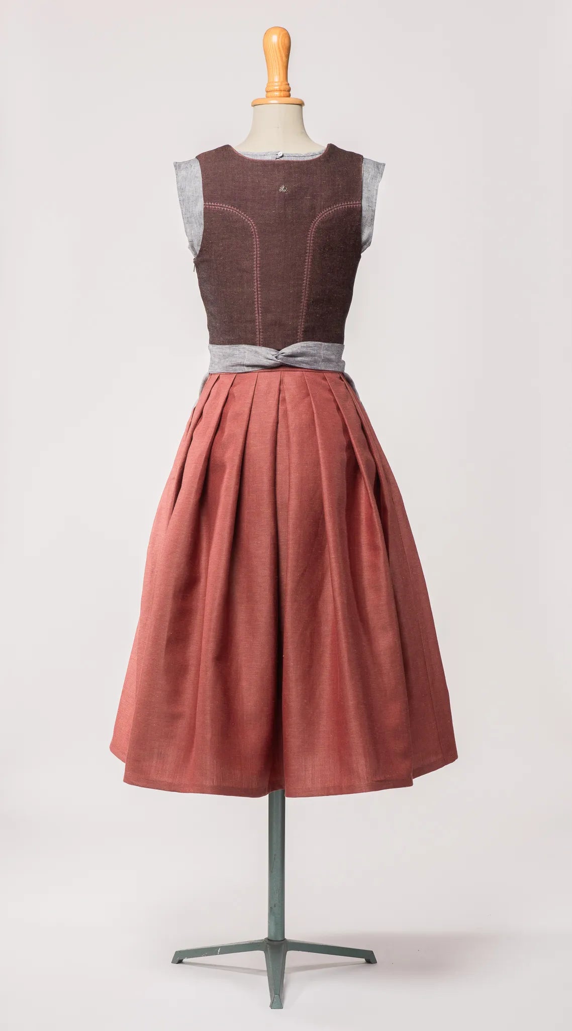 Mieder Ava aus Leinen-Schurwolle-Mischung in Beerenton, kombiniert mit Rock Marlene in pinker Beere und blaugrauer Leinenschürze – Rückansicht auf Büste, handgefertigt in München von Zirbenfux