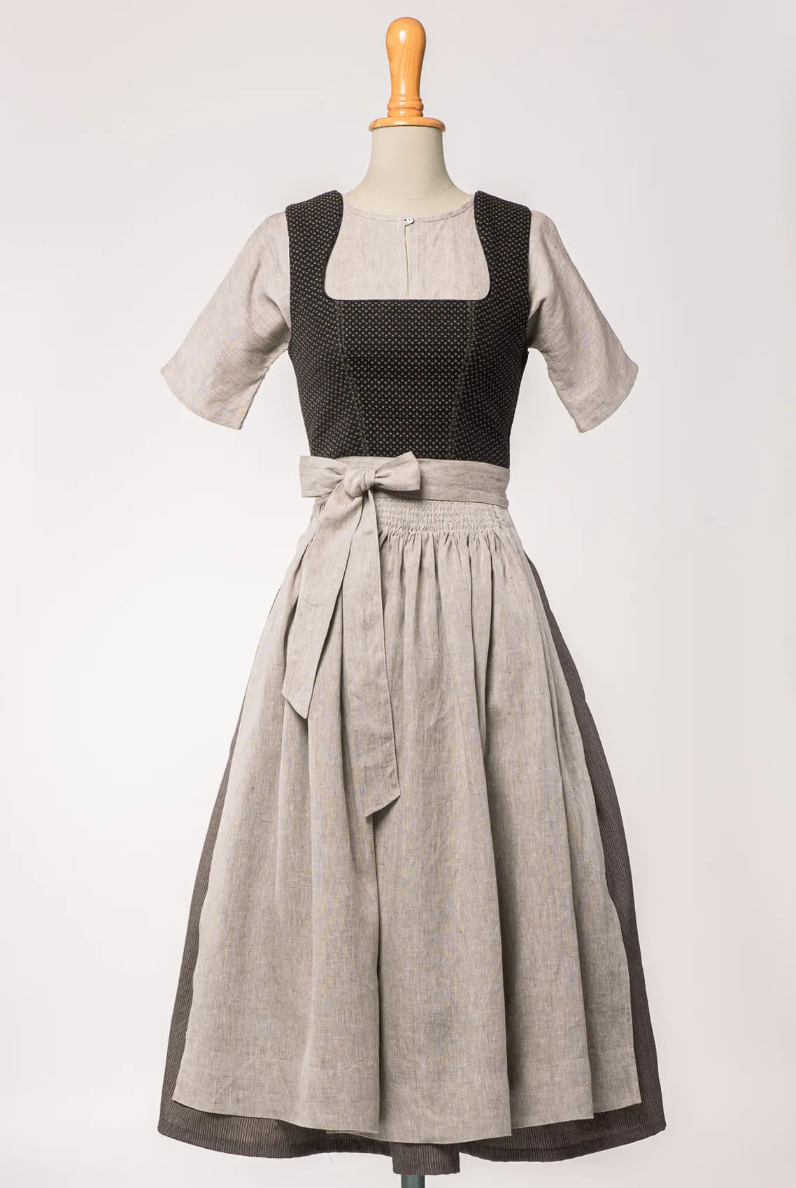 Mieder Ava aus schwarzer Schurwolle mit Webmuster, kombiniert mit Rock Marlene und naturfarbener Leinenschürze – Frontansicht auf Büste, handgefertigt in München von Zirbenfux