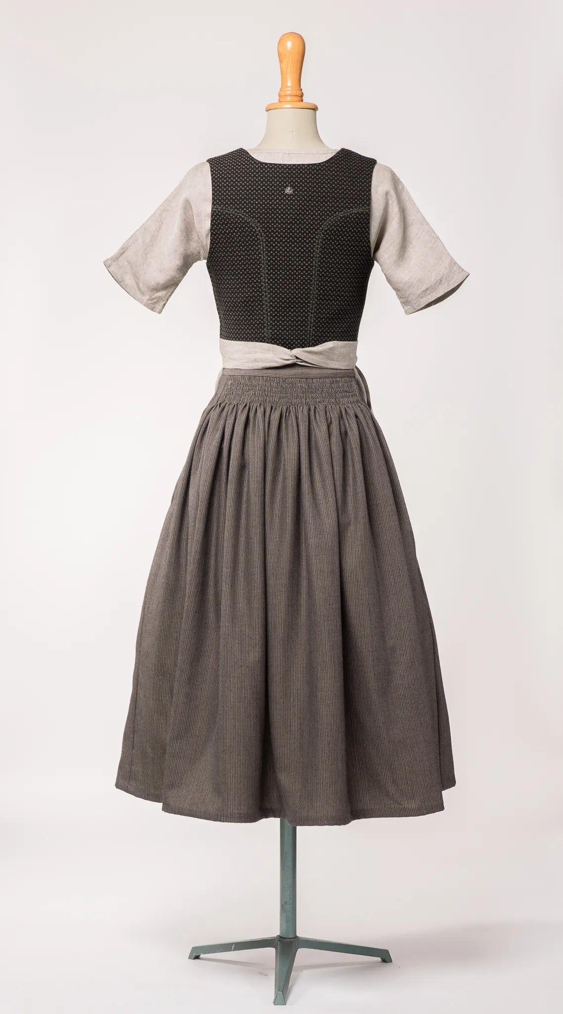 Mieder Ava aus schwarzer Schurwolle mit Webmuster, kombiniert mit Rock Marlene und naturfarbener Leinenschürze – Rückansicht auf Büste, handgefertigt von Zirbenfux