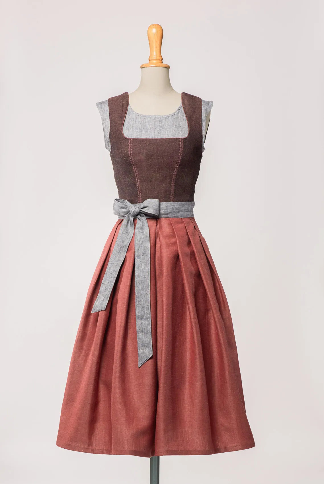 Schürzenband aus blaugrauem Bio-Leinen – kombiniert mit Mieder in Brombeere und Rock in pinker Beere, Frontansicht auf Büste, moderne Tracht von Zirbenfux