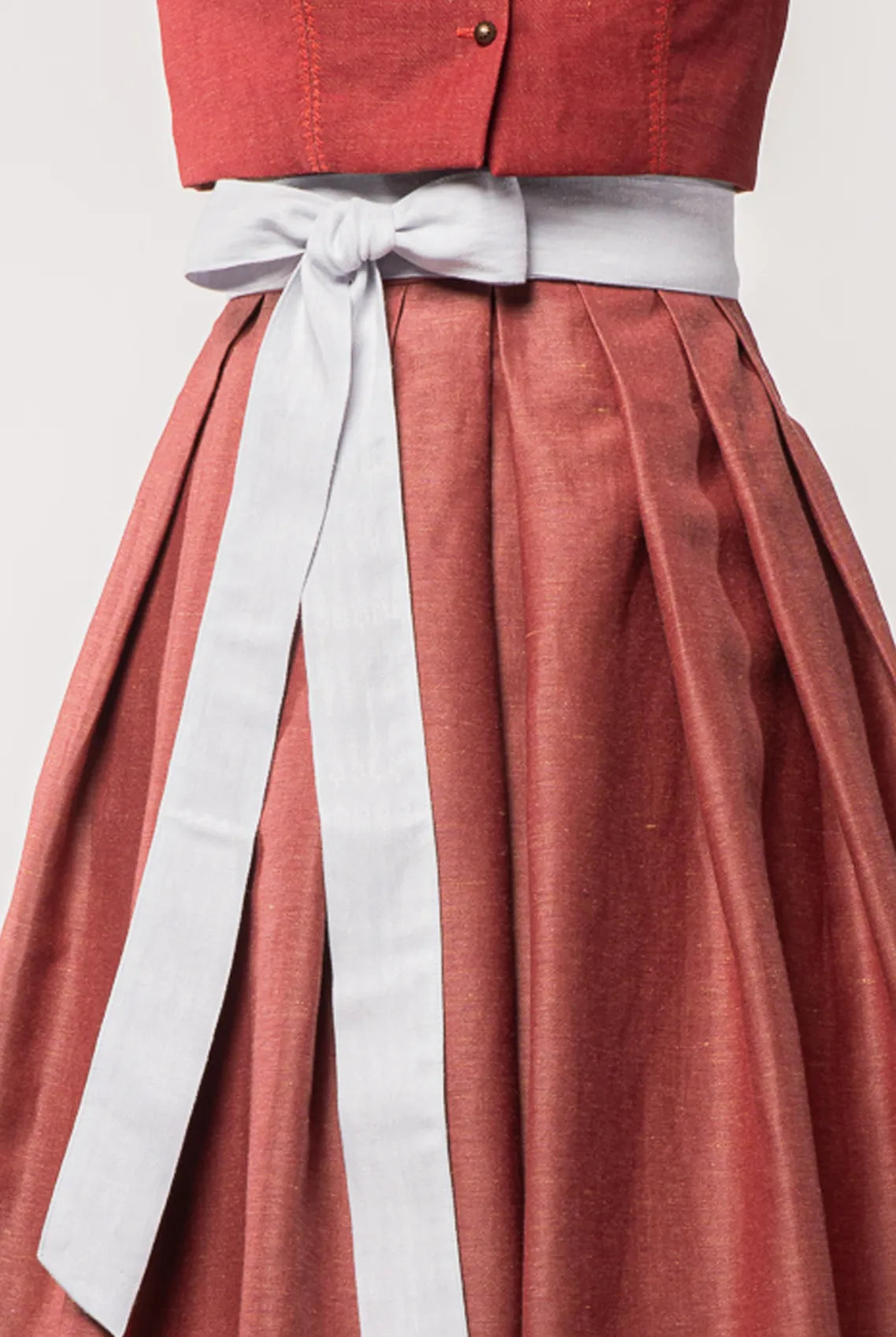 Nahaufnahme des Schürzenbands aus wasserblauem Bio-Leinen, kombiniert mit Trachtenrock Charlie in pinker Beere – Detailansicht auf Büste, moderne Tracht von Zirbenfux