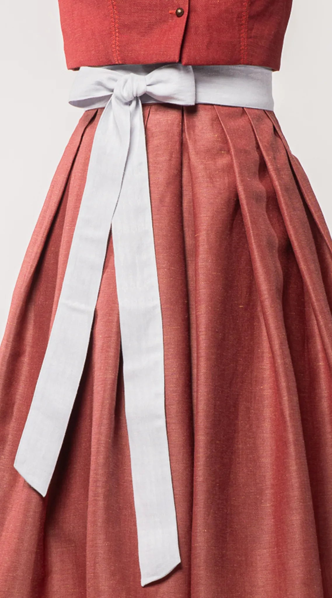 Nahaufnahme des Schürzenbands aus wasserblauem Bio-Leinen, kombiniert mit Trachtenrock Charlie in pinker Beere – Detailansicht auf Büste, moderne Tracht von Zirbenfux