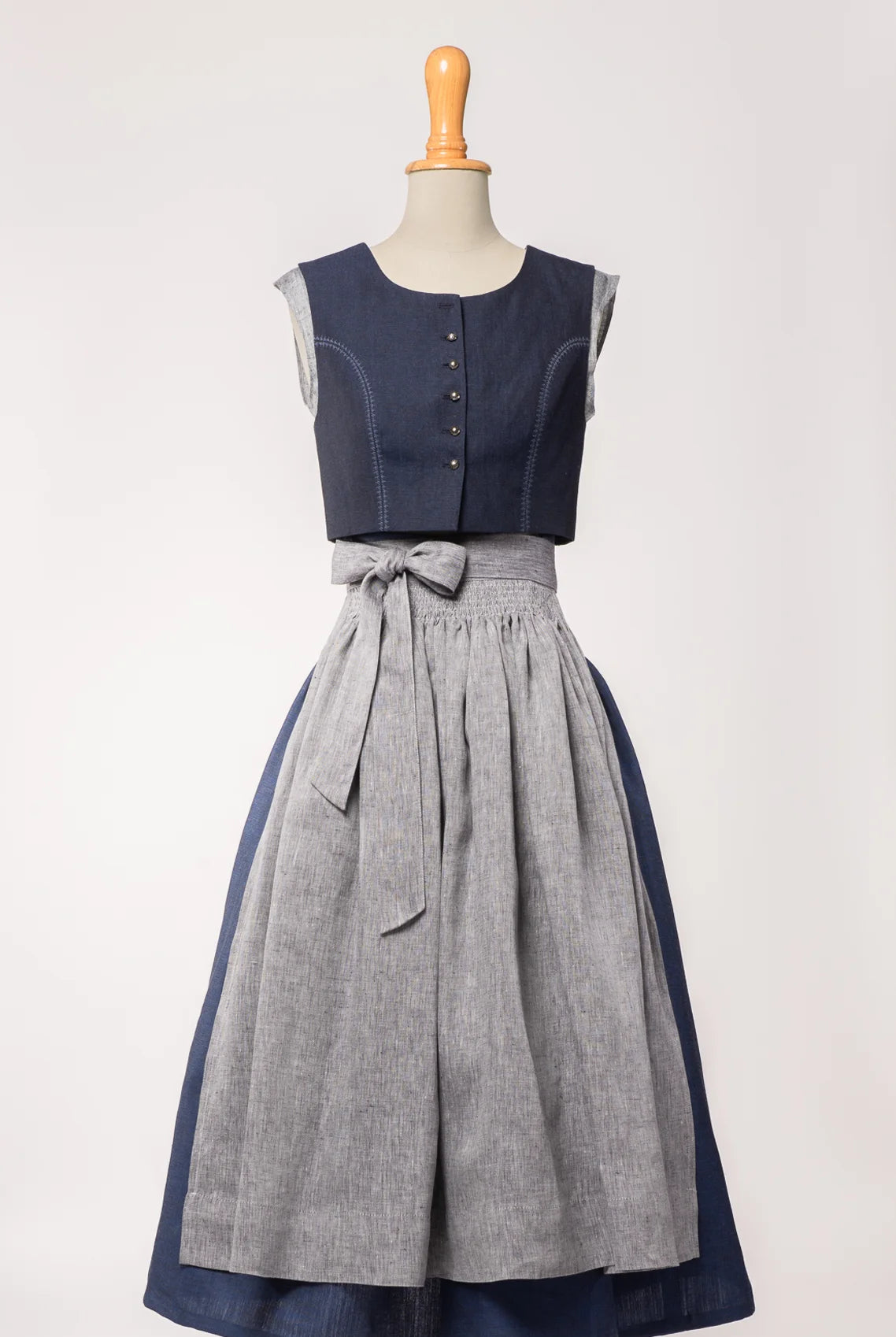 Trachtenrock Marlene aus dunkelblauer Leinen-Schurwolle-Mischung, kombiniert mit farblich passendem Fuxerl Charlie und Schürze aus blaugrauem Bio-Leinen – Frontansicht auf Büste, handgefertigt in München von Zirbenfux