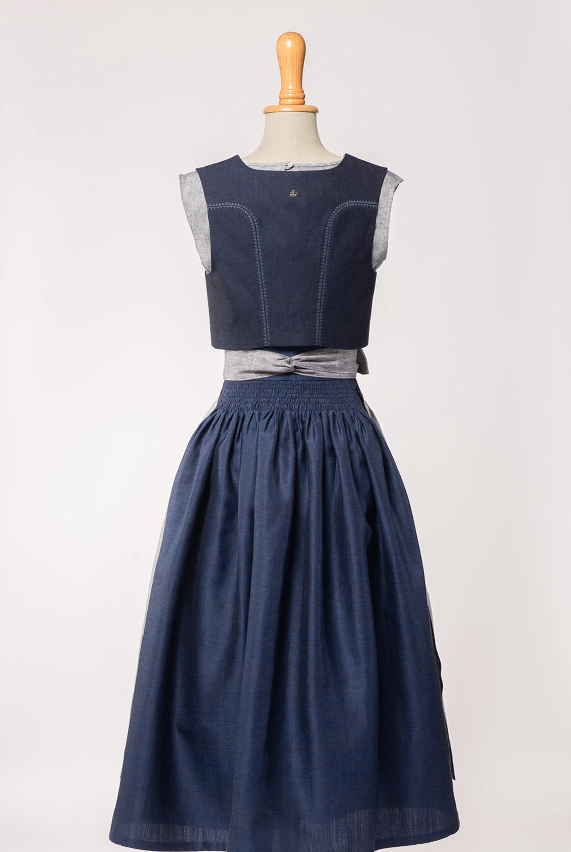 Trachtenrock Marlene aus dunkelblauer Leinen-Schurwolle-Mischung, kombiniert mit farblich passendem Fuxerl Charlie und Schürze aus blaugrauem Bio-Leinen – Rückansicht auf Büste, handgefertigt von Zirbenfux
