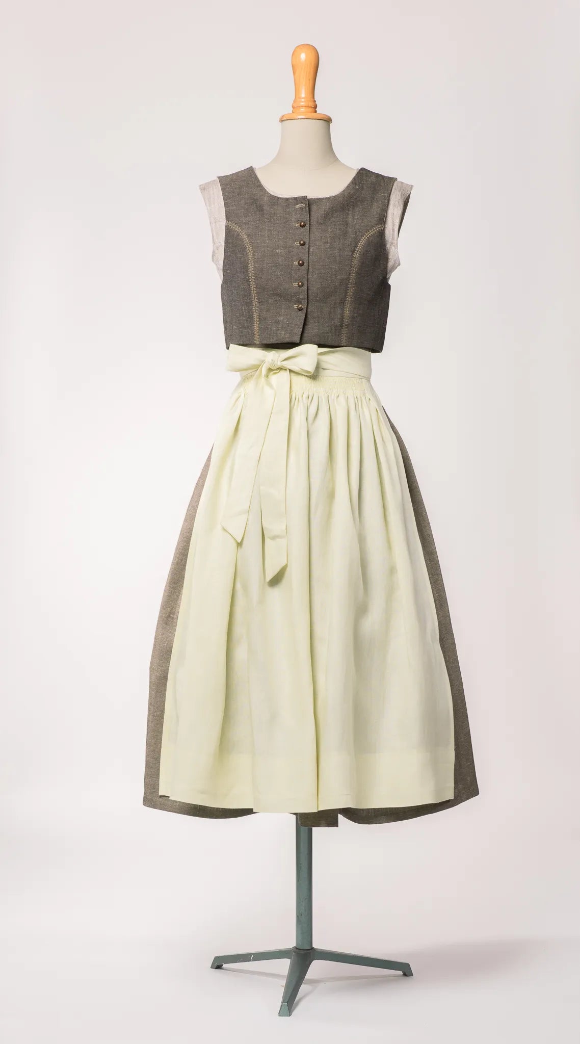 Trachtenrock Marlene aus gold-naturfarbener Leinen-Schurwolle-Mischung, kombiniert mit Fuxerl Charlie und buttergelber Leinenschürze – Frontansicht auf Büste, handgefertigt in München von Zirbenfux