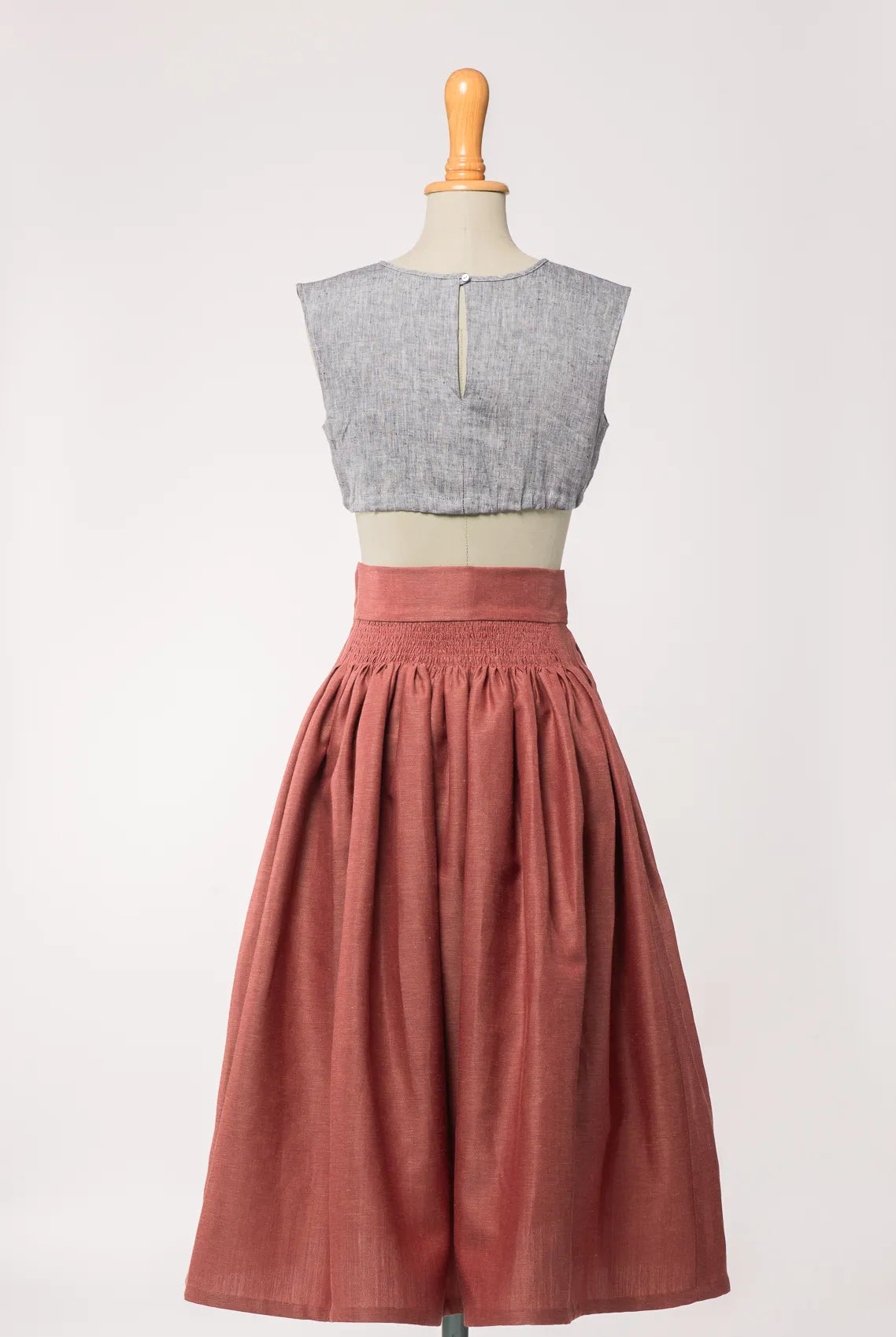 Trachtenrock Marlene aus Leinen-Schurwolle-Mischung in pinker Beere, kombiniert mit Dirndlbluse Charlie aus blaurauem Bio-Leinen – Rückansicht auf Büste, handgefertigt in München von Zirbenfux