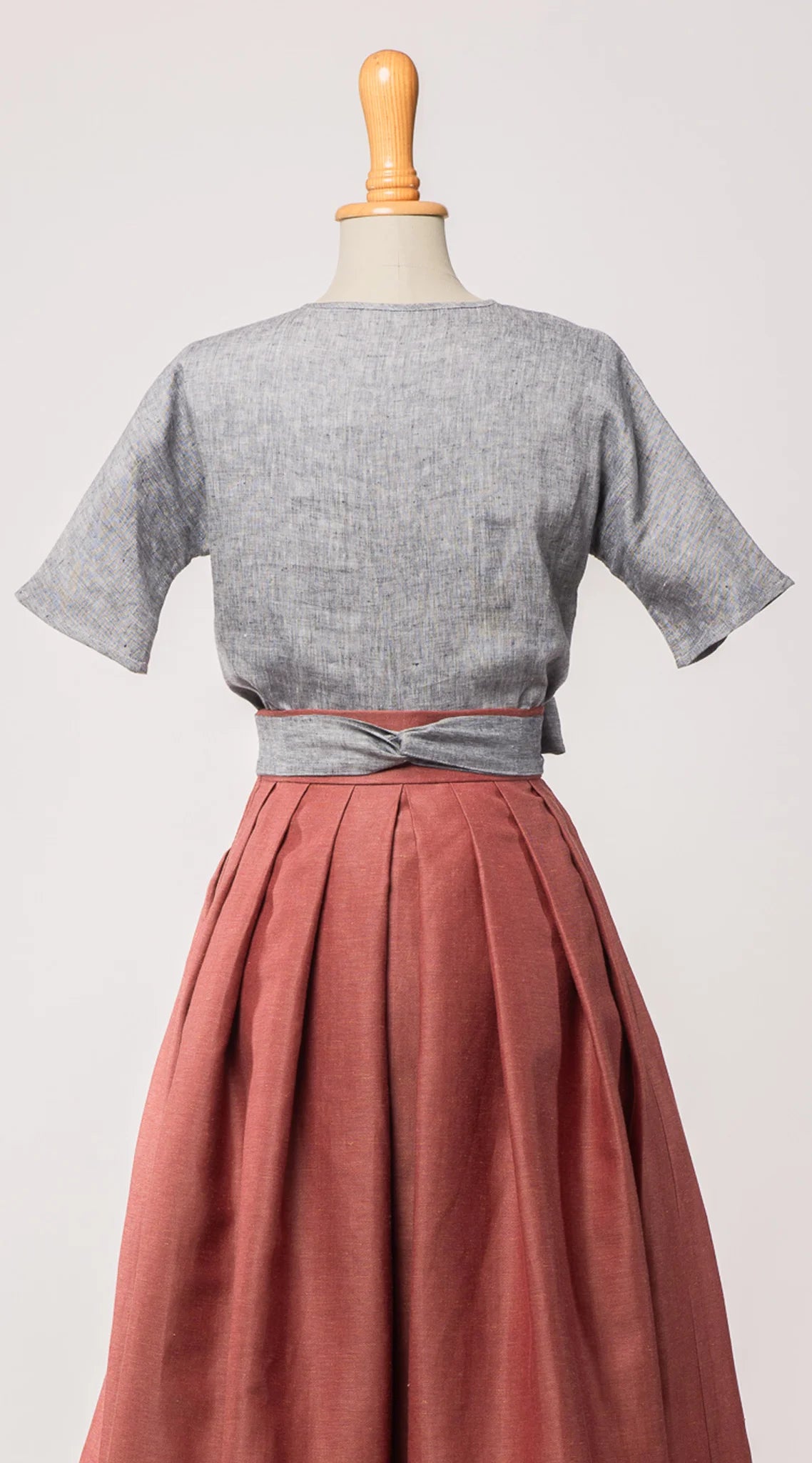 Bluse Romy aus blaugrauem Bio-Leinen, kombiniert mit Trachtenrock Charlie und farblich passendem Schürzenband – Rückansicht auf Büste, nachhaltig gefertigt von Zirbenfux