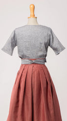 Bluse Romy aus blaugrauem Bio-Leinen, kombiniert mit Trachtenrock Charlie und farblich passendem Schürzenband – Rückansicht auf Büste, nachhaltig gefertigt von Zirbenfux