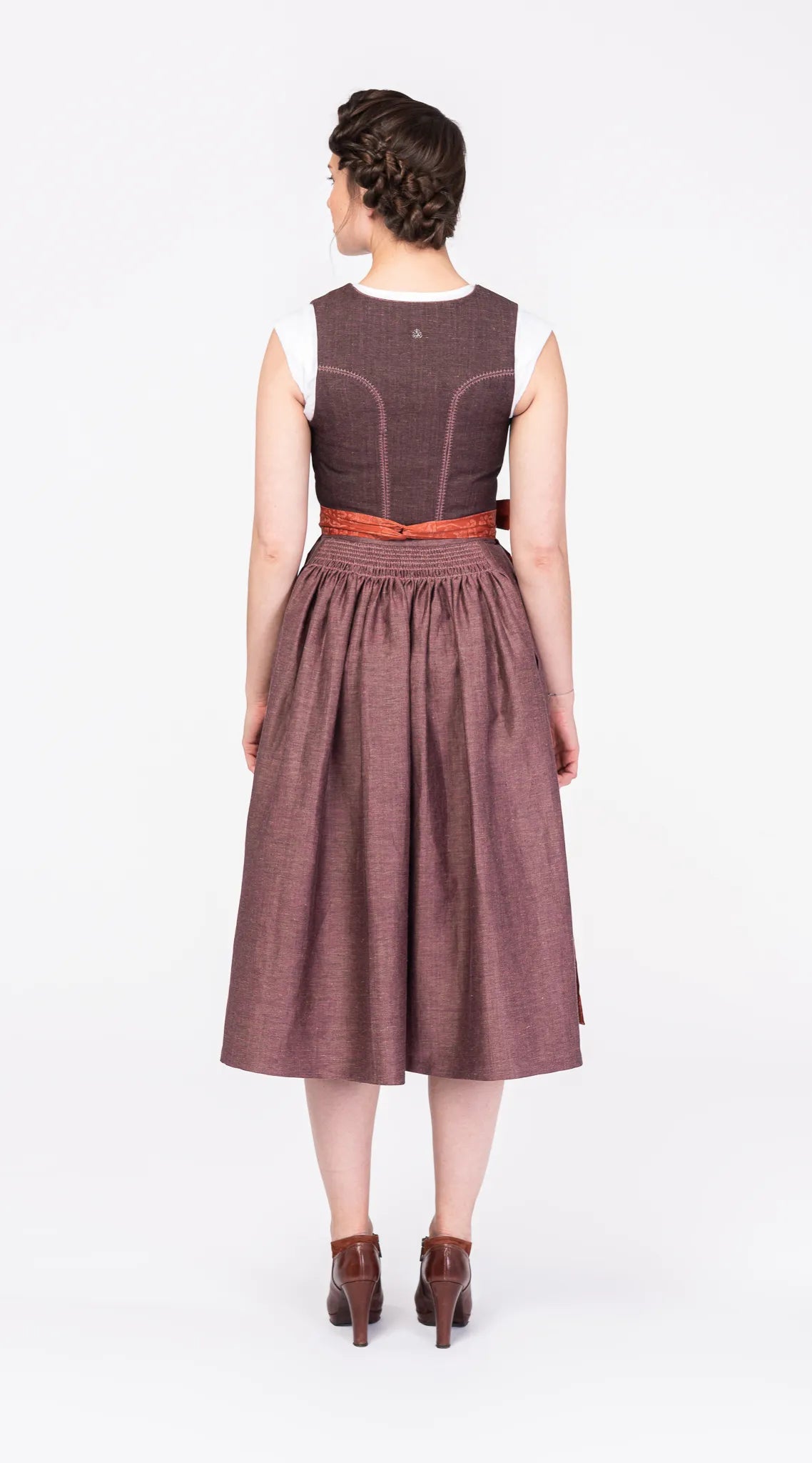 Dirndl Ava aus Leinen in Malve mit Schürze in Terrakotta – Rückansicht am Model, handgefertigt in München von Zirbenfux