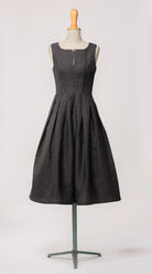 Hochgeschlossenes Dirndl Wanda von Zirbenfux in Anthrazit aus regional gewebtem Leinen-Wolle-Mix, mit filigraner Schließe und in Falten gelegtem Rock, an einer Schneiderbüste.