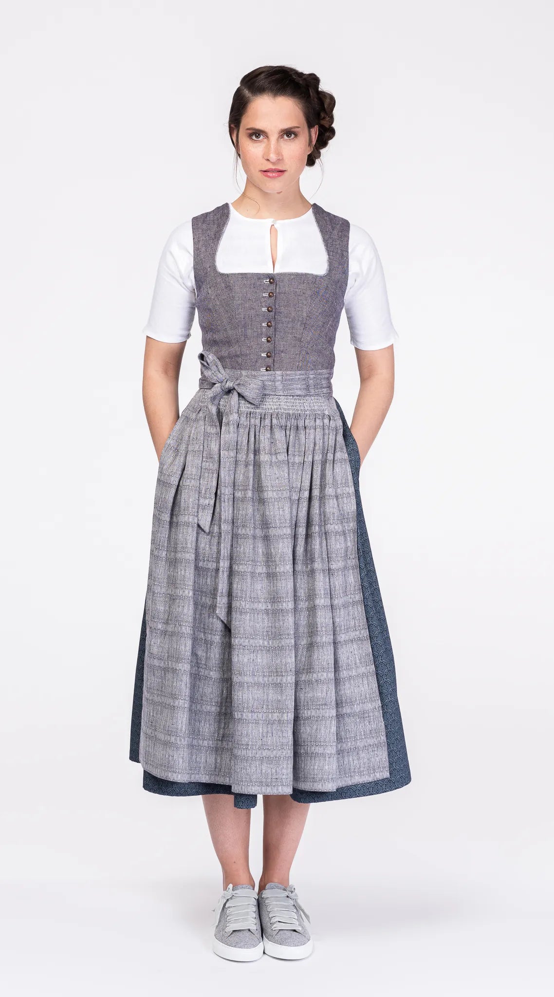 Dirndlschürze aus blaugrauem Bio-Leinen mit eingewebtem Muster – Frontansicht am Model, kombiniert mit blauem Leinendirndl, nachhaltig gefertigt von Zirbenfux