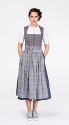 Dirndlschürze aus blaugrauem Bio-Leinen mit eingewebtem Muster – Frontansicht am Model, kombiniert mit blauem Leinendirndl, nachhaltig gefertigt von Zirbenfux