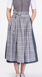 Dirndlschürze aus blaugrauem Bio-Leinen mit eingewebtem Muster – Nahaufnahme Frontansicht am Model, nachhaltig gefertigt von Zirbenfux