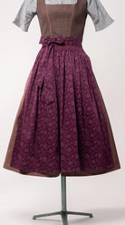 Dirndlschürze aus brombeerfarbener Baumwolle mit Blumenrankenmuster – Nahaufnahme der Frontansicht auf Büste, handgefertigt in München von Zirbenfux