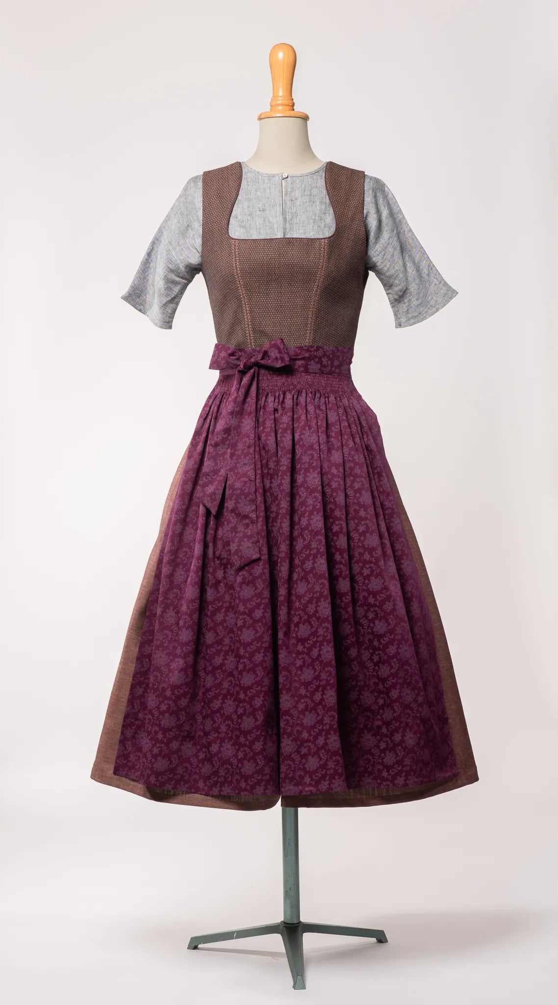 Dirndlschürze aus brombeerfarbener Baumwolle mit Blumenrankenmuster – Frontansicht auf Büste, kombiniert mit Dirndl in Beerentönen, moderne Tracht von Zirbenfux