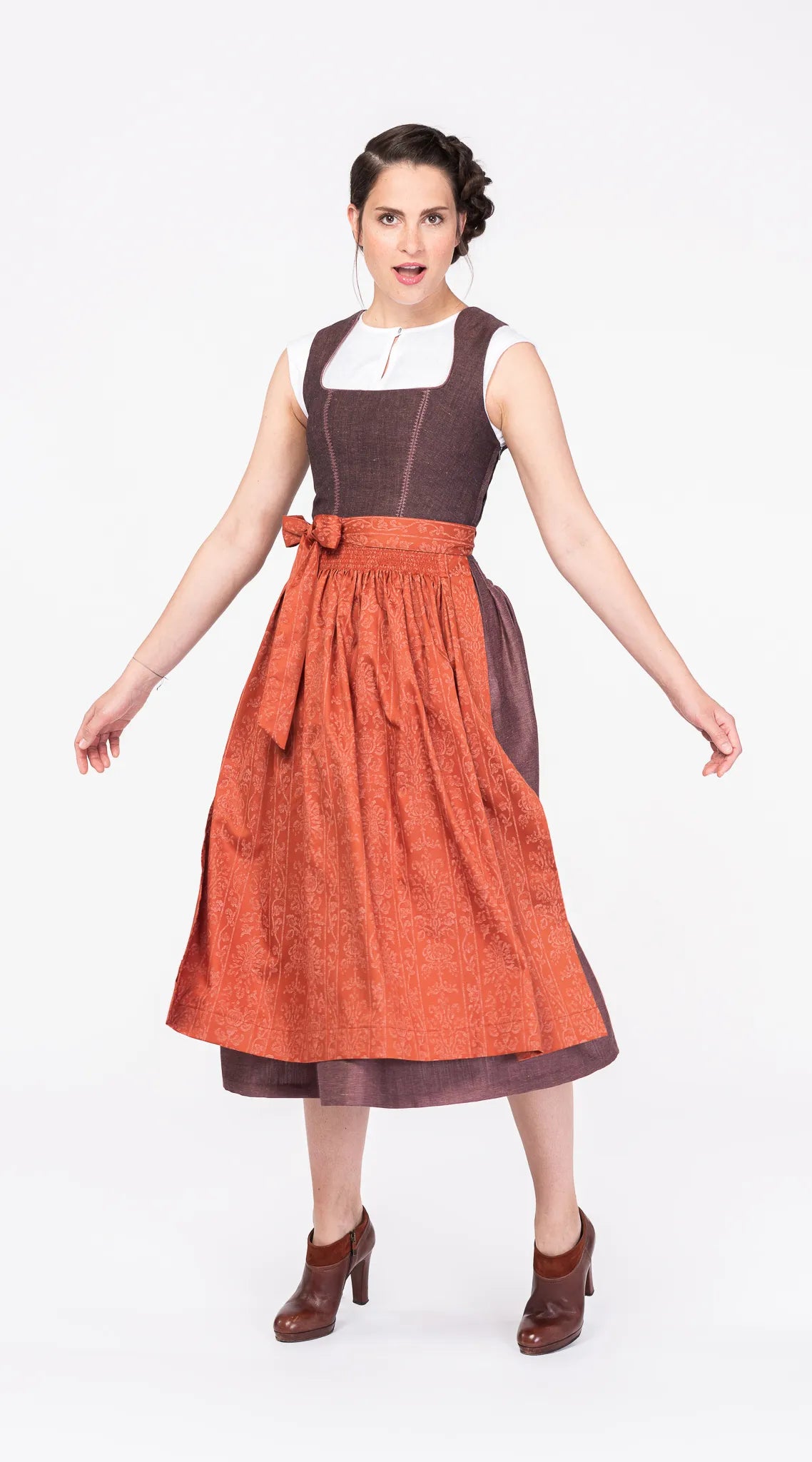 Dirndlschürze aus Baumwolle in Orange-Terrakotta – am Model in Bewegung, nachhaltig gefertigt von Zirbenfux