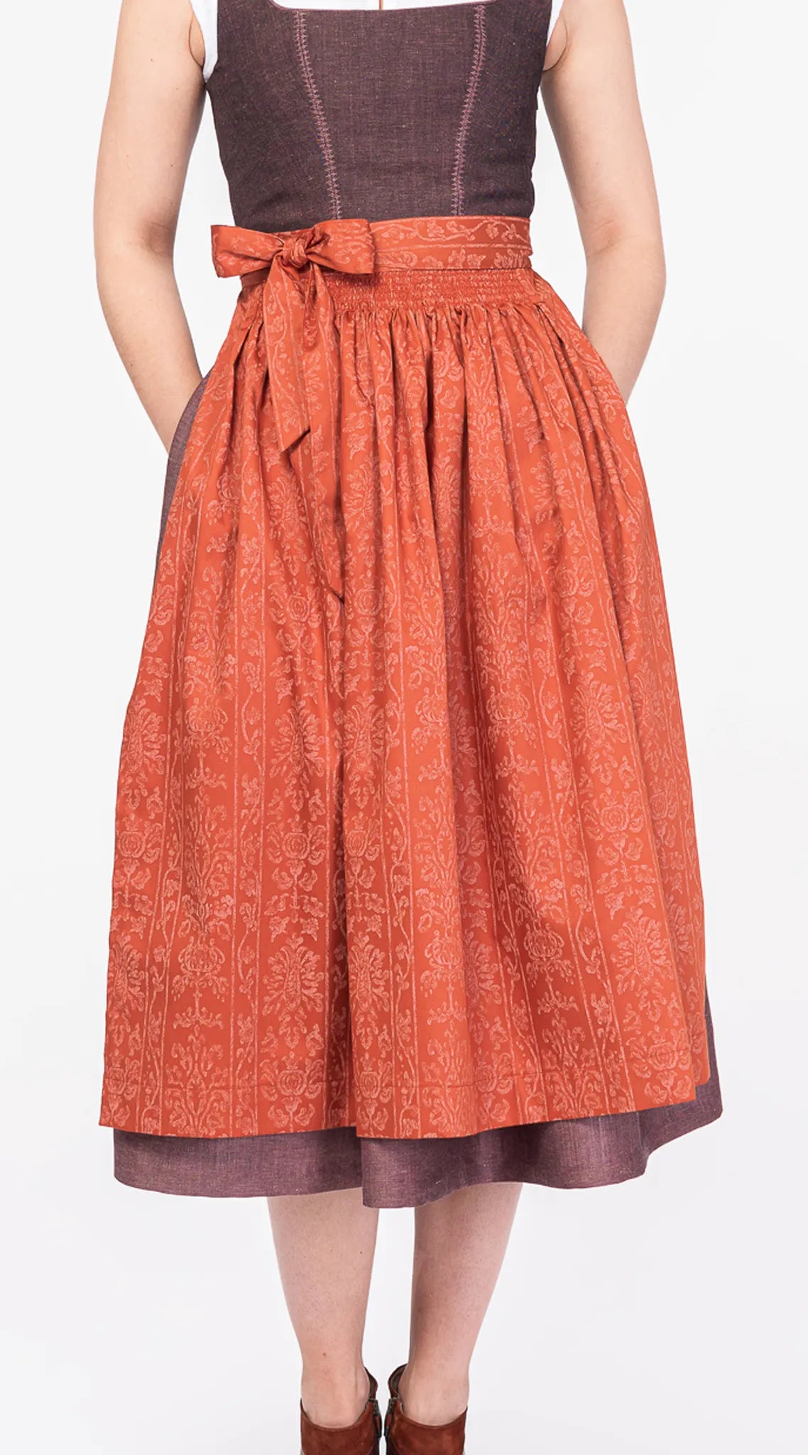 Dirndlschürze aus Baumwolle in Orange-Terrakotta – Nahaufnahme der Frontansicht am Model, handgefertigt von Zirbenfux