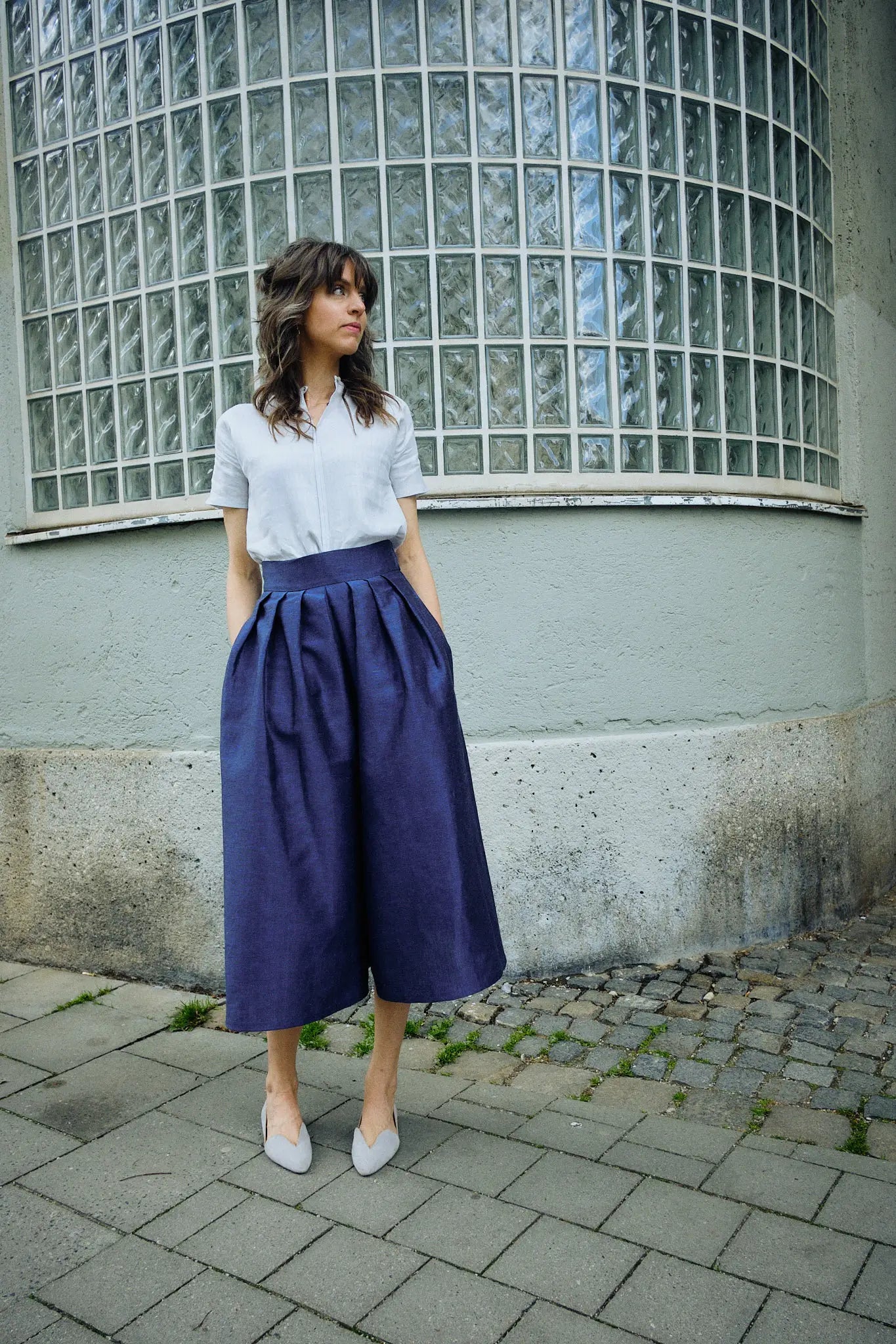 Hosenrock Audrey mit Bluse Romy im Set in Blau aus Leinen, Model locker stehend in Frontansicht auf der Straße im urbanen Setting, klar inszeniert von Zirbenfux.