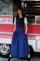 Hosenrock Audrey mit Fuxerl Charlie im Set in Dunkelblau aus Leinen, Model lässig mit dem Rücken an einen Straßenimbiss gelehnt und die Hände in den Taschen, urban inszeniert von Zirbenfux.