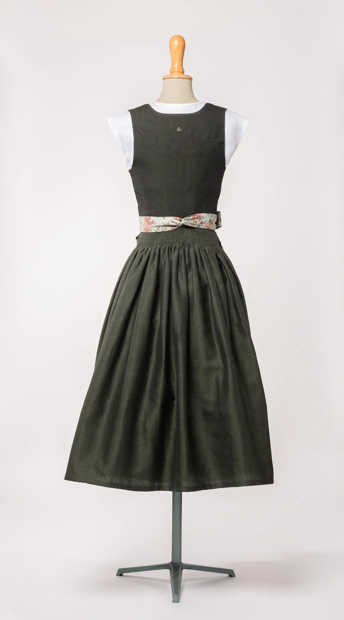 Mieder Ava aus dunkelgrüner Leinen-Schurwolle-Mischung, kombiniert mit Schürze mit Blumenmuster – Rückansicht auf Büste, handgefertigt in München von Zirbenfux