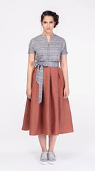 Schürzenband aus blaugrauem Bio-Leinen mit eingewebtem Muster, kombiniert mit Leinenbluse im gleichen Farbton und Rock in Terrakotta – Frontansicht am Model, handgefertigt von Zirbenfux
