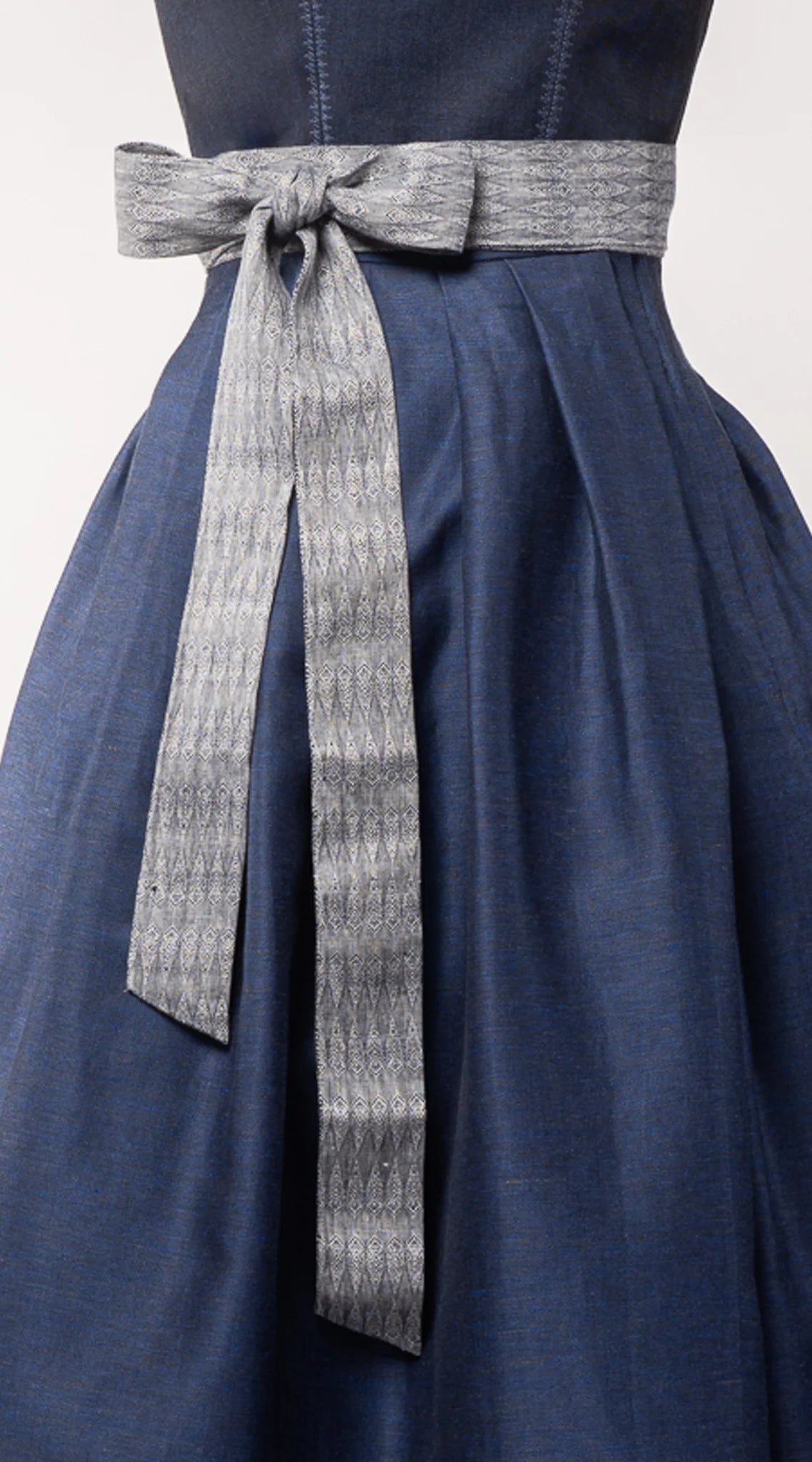 Nahaufnahme des Schürzenbands aus blaugrauem Bio-Leinen mit eingewebtem Muster – fein verarbeitet, handgefertigt in München von Zirbenfux